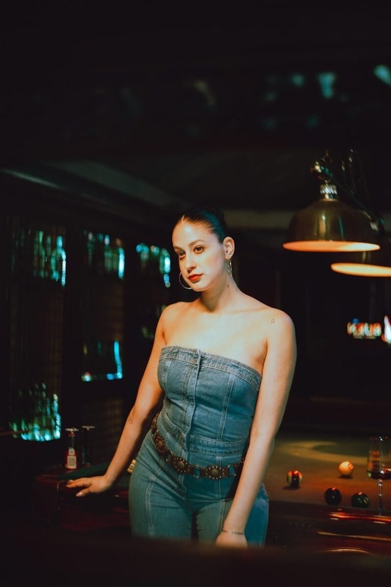 Woman in denim night outfit poses by a pool table