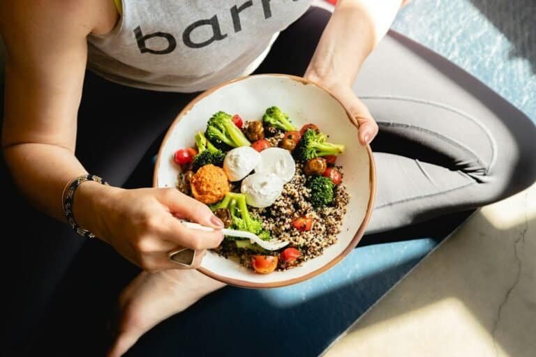 a woman is holding a vegetable bowl of food
